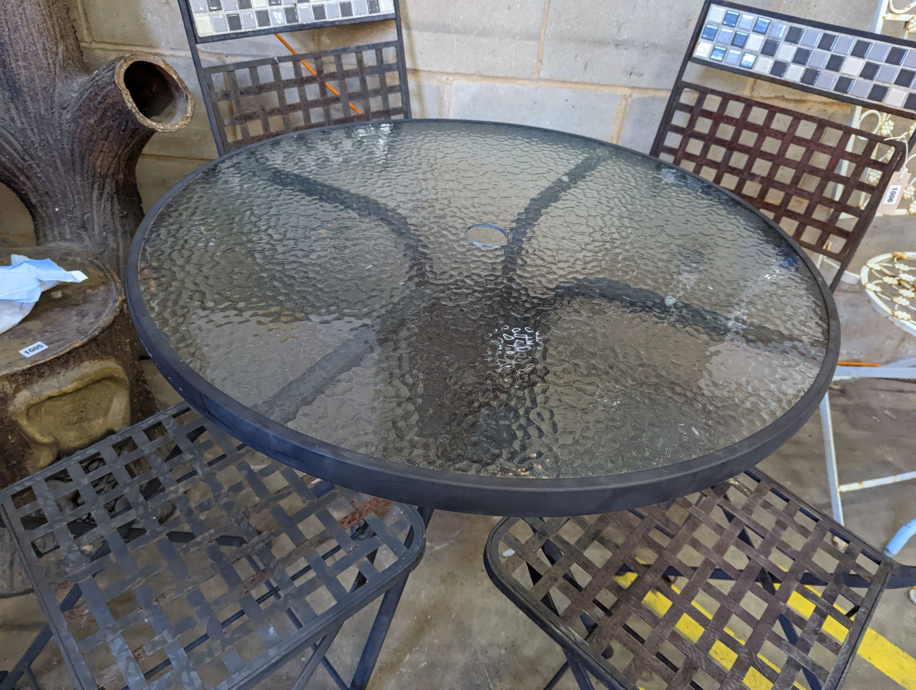 A circular glass top garden table, diameter 80cm, height 71cm and four metal folding garden chairs